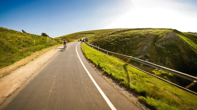 Un ciclista pedalea con expresión seria en la ladera de una carretera rural