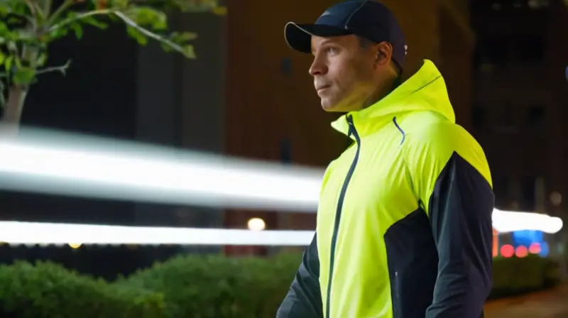 Un hombre camina por la ciudad vestido con ropa para correr brillante y impermeabilizadora