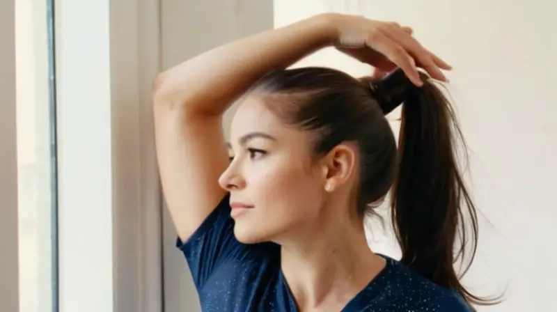 Una joven mujer con el cabello oscuro atado en una cola de caballo se estira inclinando su cuerpo hacia la izquierda por una puerta redondeada, iluminada por un brillo agradable que destaca su expresión facial relajada