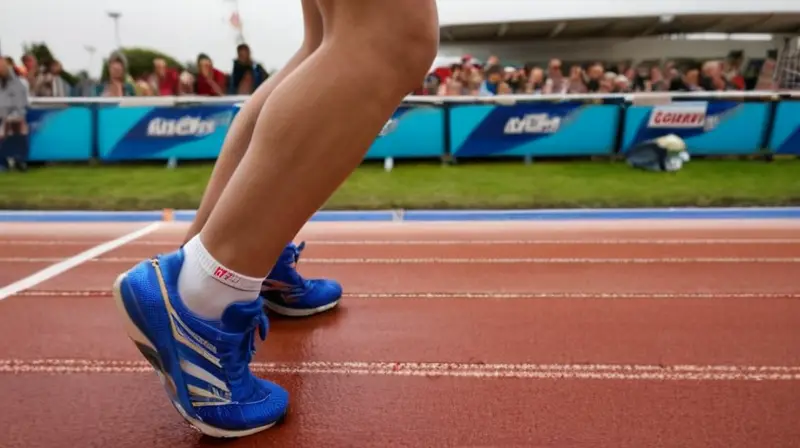 Un joven atleta de velocidad se alinea en el punto de partida mientras su mirada se concentra intensamente hacia adelante