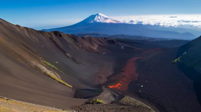 Etna es un volcán rodeado por una paisaje montañoso con terreno erosionado, bosques y un lago en sus faldas