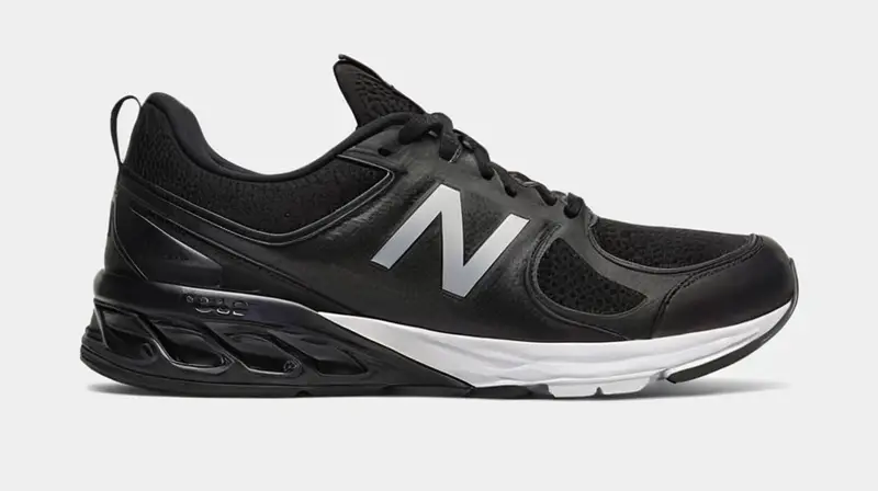 Un zapato deportivo negro elegante con detalles refinados y precisos que destacan bajo la luz tenue