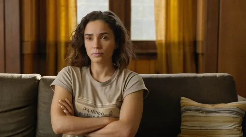 Una mujer está sentada en un sofá antiguo con una camiseta desgastada y un libro por leer