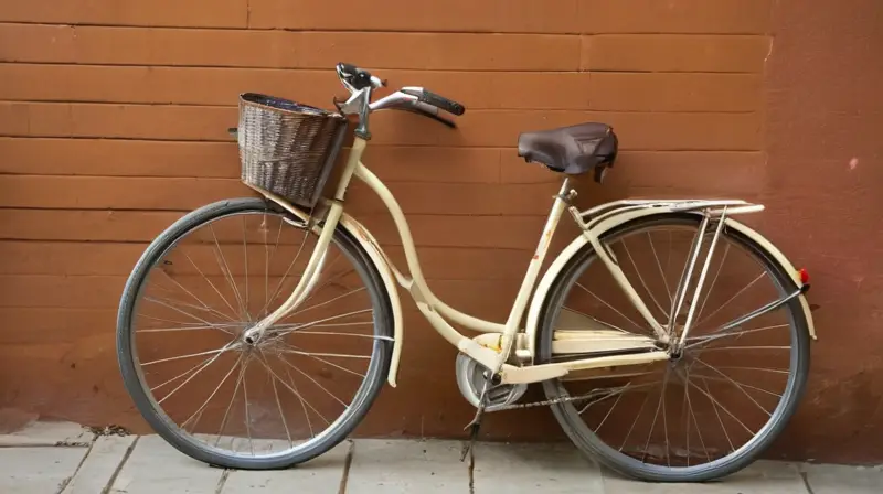 Una bicicleta oxidada y desgastada está apoyada en una pared de ladrillos grises erosionados bajo la luz suave del final de la tarde