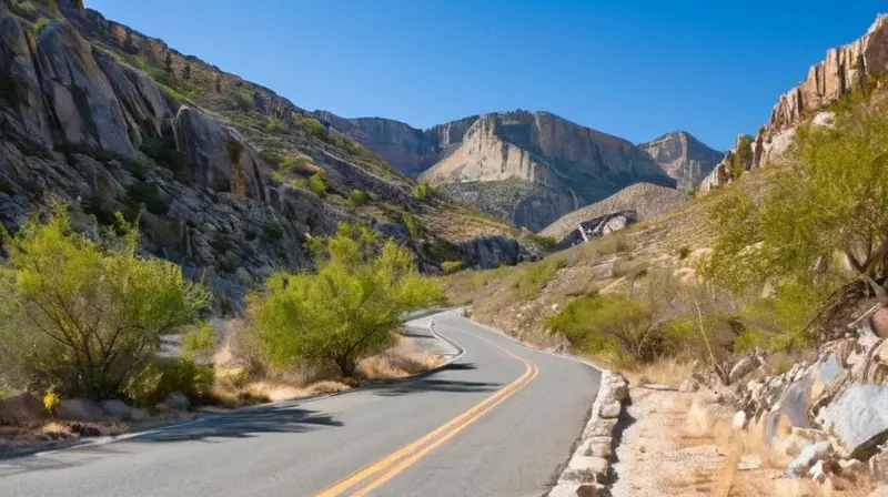 Un camino de montaña desgastado vira hacia arriba desde un valle distante y atraviesa un paisaje rocoso con árboles muertos