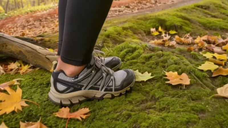 Un corredor calza sus zapatos negros y grises en un terreno verdecido rodeado de hojas caídas y arbustos densos bajo el sol difuso del otoño