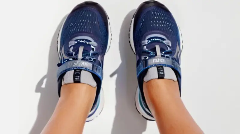 Las manos de una mujer sostienen unas zapatillas de correr grises elegantes sobre un fondo blanco iluminadas por luz natural brillante